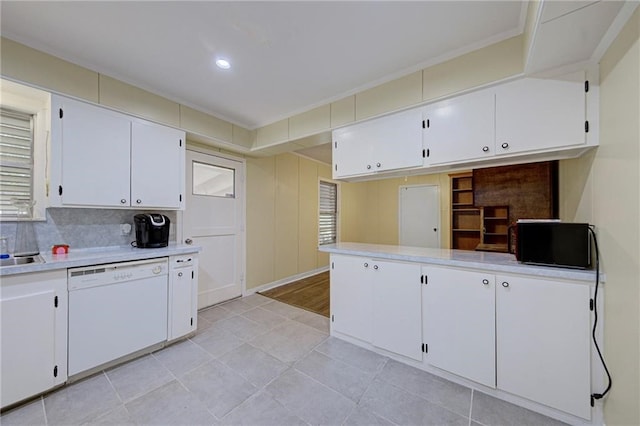 kitchen with sink, kitchen peninsula, tasteful backsplash, white dishwasher, and white cabinets