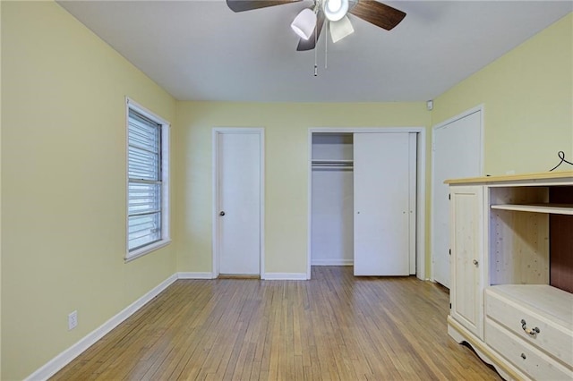 unfurnished bedroom with light wood-type flooring, ceiling fan, and two closets