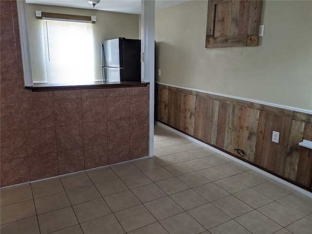 tiled spare room featuring wooden walls