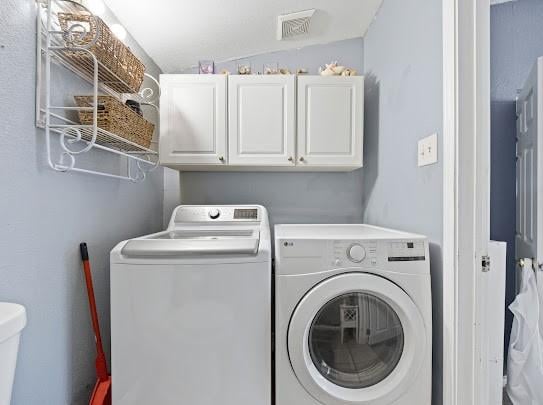 clothes washing area featuring cabinets and washer and dryer