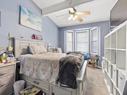 carpeted bedroom with lofted ceiling with beams and ceiling fan