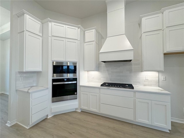 kitchen featuring light hardwood / wood-style flooring, white cabinets, custom range hood, and gas stovetop