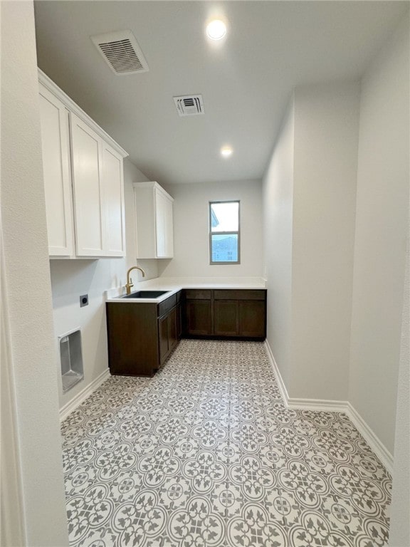 clothes washing area with electric dryer hookup, cabinets, and sink