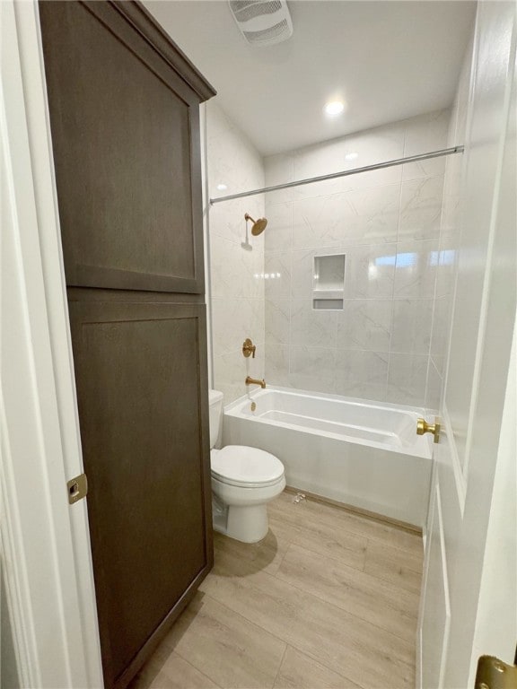 bathroom featuring toilet, hardwood / wood-style floors, and tiled shower / bath