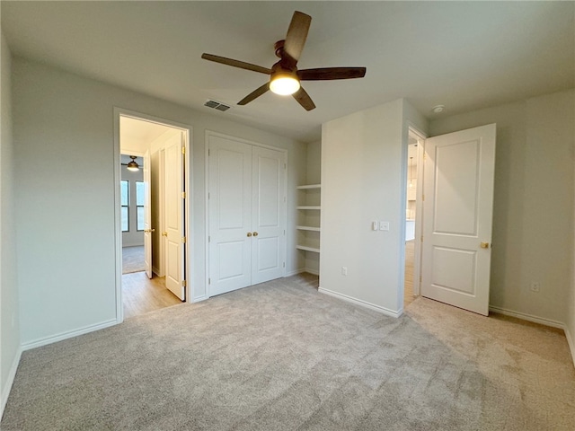 unfurnished bedroom featuring ceiling fan, a closet, and light carpet