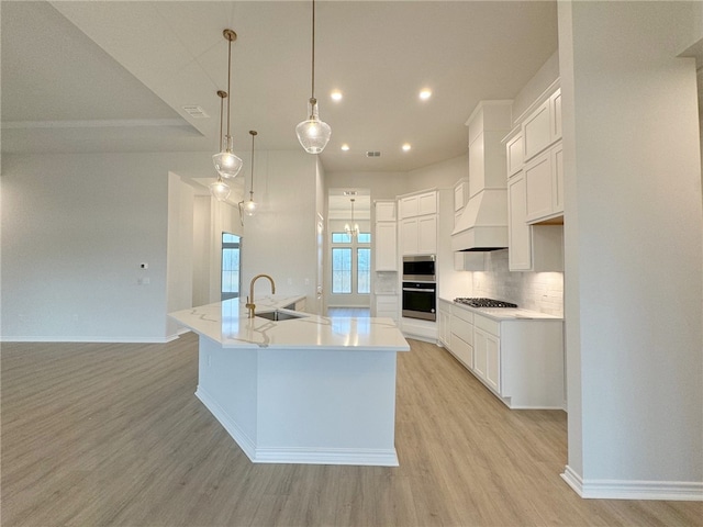 kitchen featuring a large island, light hardwood / wood-style floors, white cabinetry, and sink