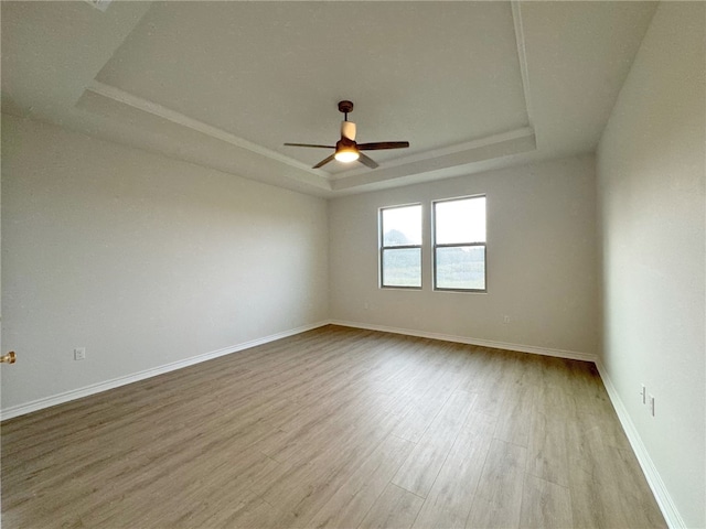 unfurnished room featuring a tray ceiling, ceiling fan, and light hardwood / wood-style floors