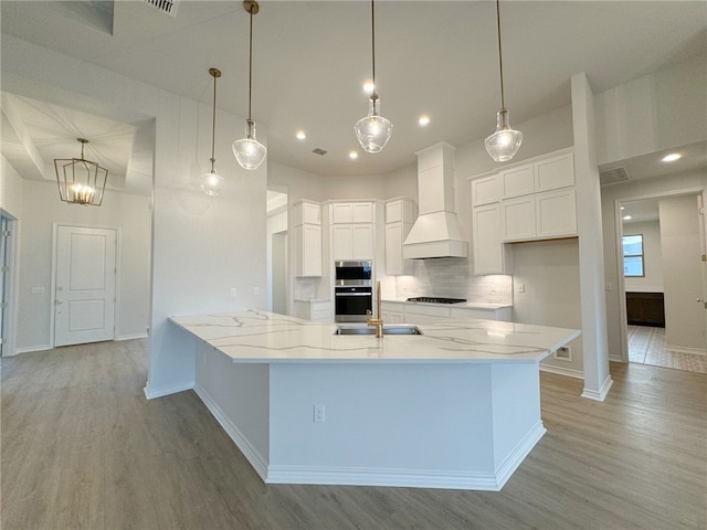 kitchen featuring pendant lighting, white cabinets, light wood-type flooring, and custom exhaust hood