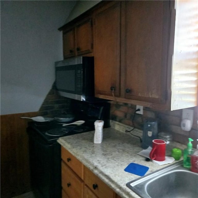 kitchen with stainless steel microwave, black electric range oven, light countertops, and a sink