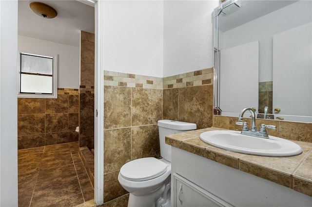 bathroom featuring tile patterned floors, vanity, toilet, and tile walls