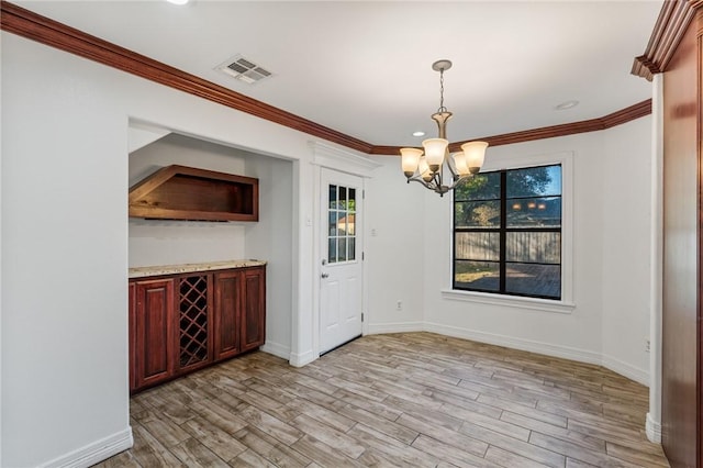 unfurnished dining area featuring an inviting chandelier, ornamental molding, and light wood-type flooring