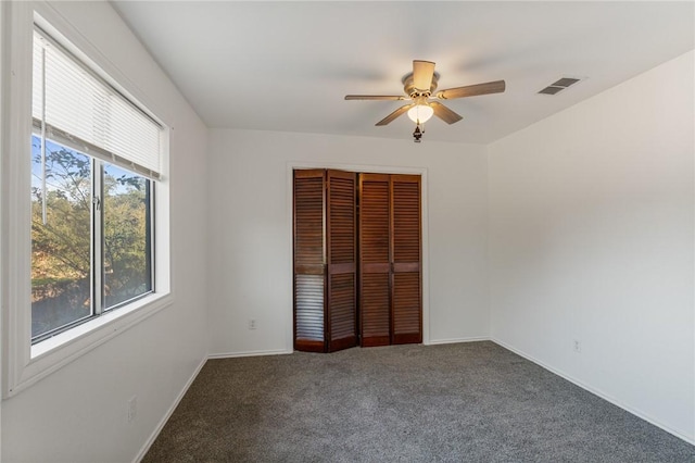 unfurnished bedroom with a closet, dark carpet, and ceiling fan