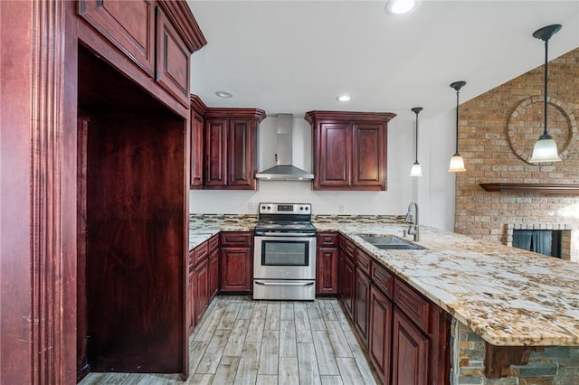 kitchen featuring sink, hanging light fixtures, wall chimney range hood, light hardwood / wood-style floors, and stainless steel electric stove