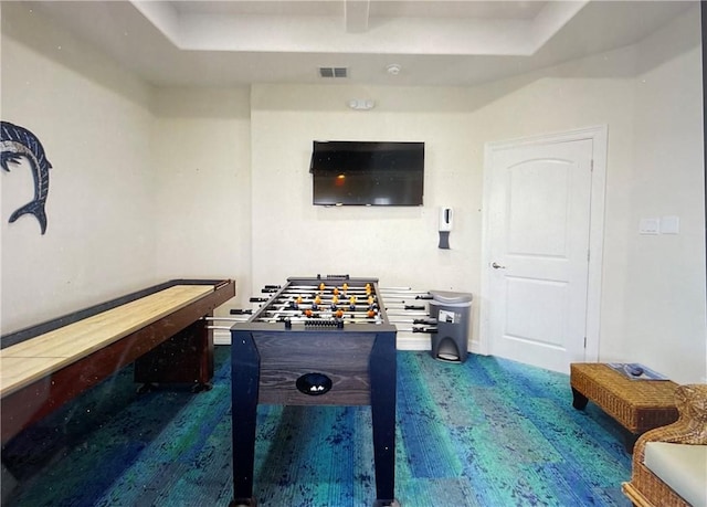 game room featuring a tray ceiling and dark wood-type flooring