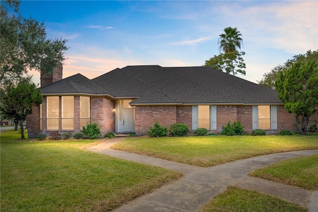 5305 Hunt Cir, Corpus Christi, TX 78413 - view of front facade with a yard, a chimney, brick siding, and roof with shingles