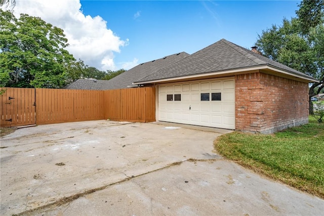 5305 Hunt Cir, Corpus Christi, TX 78413 - view of property exterior with roof with shingles, brick siding, a garage, concrete driveway, and a gate