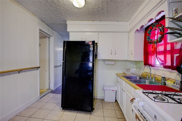 kitchen with a textured ceiling, black refrigerator, white cabinetry, and sink