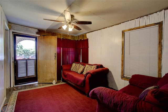 living room with ceiling fan, wooden walls, and hardwood / wood-style flooring