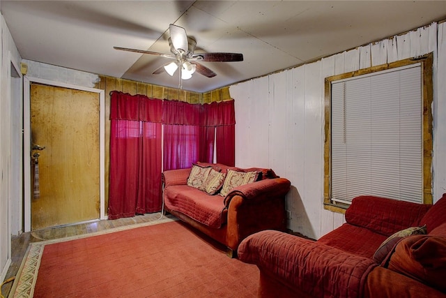 living room with ceiling fan and wooden walls