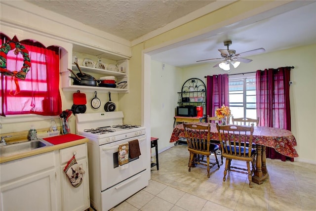 kitchen featuring white gas range, ceiling fan, sink, a textured ceiling, and white cabinets