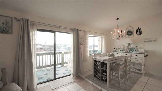 dining space featuring a water view, a chandelier, and light tile patterned flooring