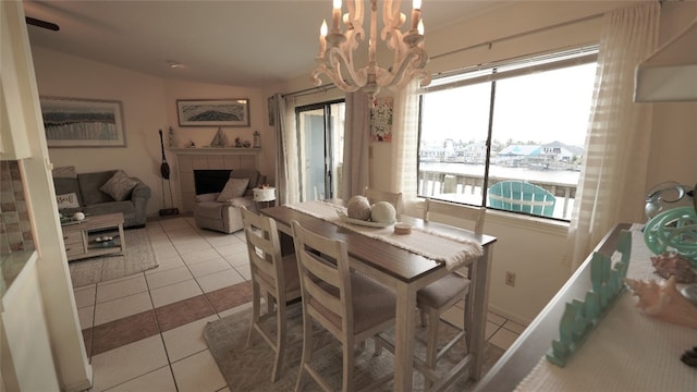 dining area with light tile patterned flooring, a water view, a chandelier, and a tile fireplace