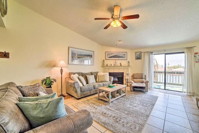 living room featuring vaulted ceiling, a tile fireplace, ceiling fan, and light tile patterned flooring