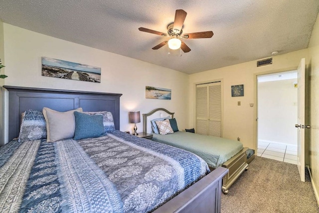 bedroom featuring tile patterned flooring, ceiling fan, a closet, and a textured ceiling