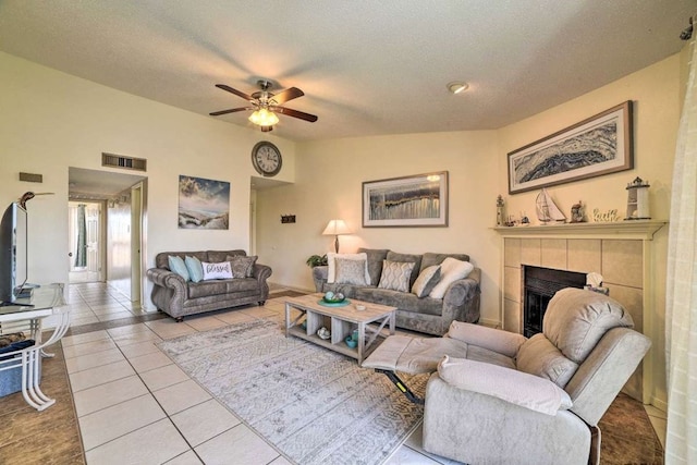 living room featuring a tile fireplace, lofted ceiling, light tile patterned floors, and a textured ceiling