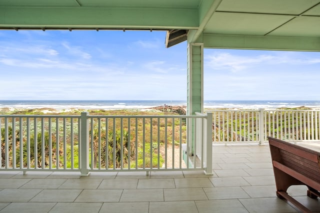 view of patio with a water view, a beach view, and a balcony