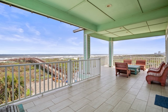 view of patio / terrace featuring a balcony, a view of the beach, and a water view