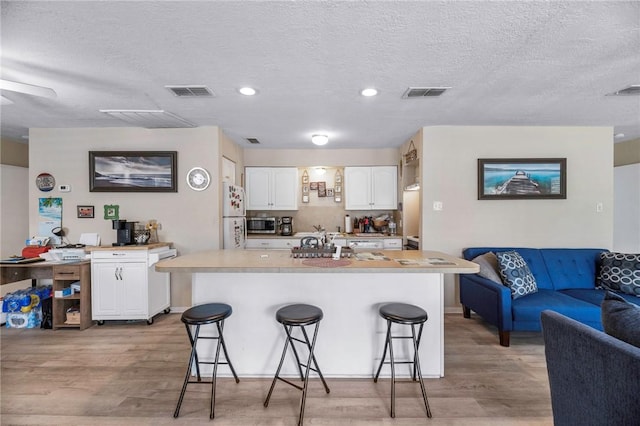 245 Griffith Dr, Rockport, TX 78382 - kitchen featuring a breakfast bar area, open floor plan, visible vents, and light wood finished floors