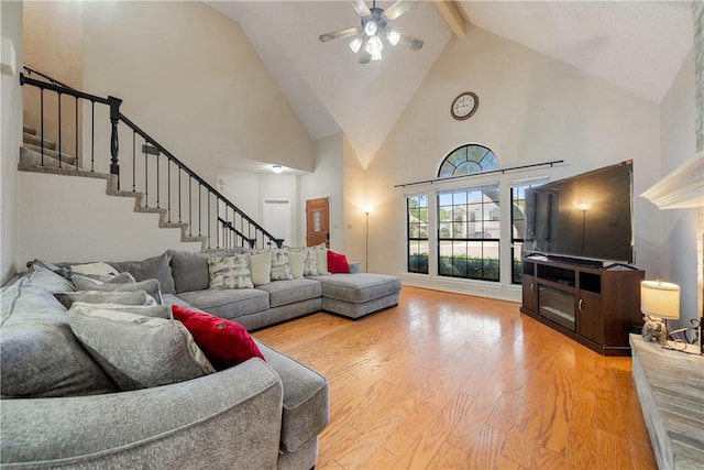 living room featuring high vaulted ceiling, stairway, a ceiling fan, hardwood / wood-style flooring, and beam ceiling