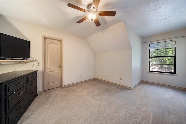 additional living space with light colored carpet, ceiling fan, baseboards, and vaulted ceiling