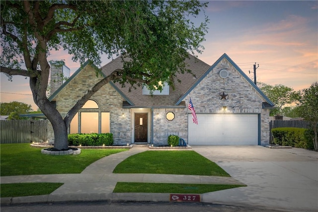 view of front of house featuring an attached garage, driveway, fence, and a front lawn