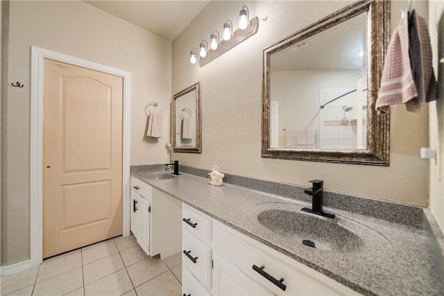 bathroom featuring tile patterned floors, a sink, double vanity, a tile shower, and visible vents