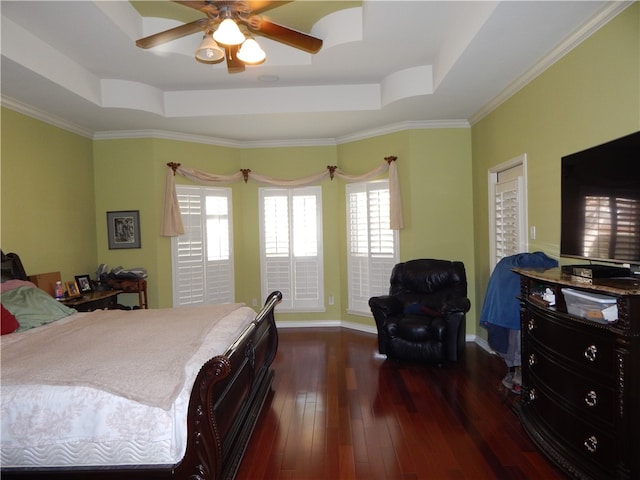 bedroom with dark wood-type flooring, ornamental molding, ceiling fan, and a raised ceiling