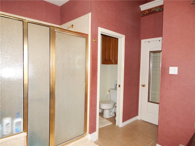 bathroom with toilet, an enclosed shower, and tile patterned floors