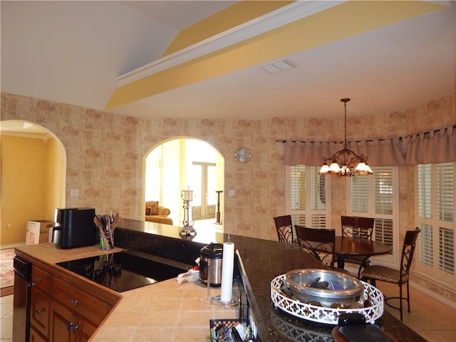 kitchen with a healthy amount of sunlight, black electric cooktop, vaulted ceiling, an inviting chandelier, and light tile patterned flooring