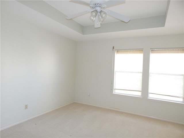 carpeted empty room featuring a tray ceiling and ceiling fan