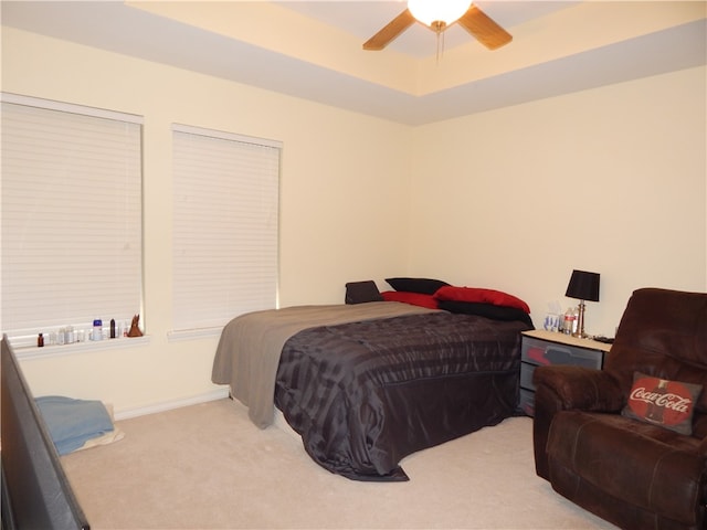 carpeted bedroom featuring ceiling fan and a raised ceiling