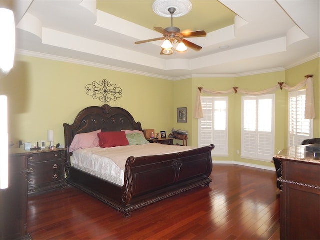 bedroom featuring dark wood-type flooring, crown molding, and a raised ceiling