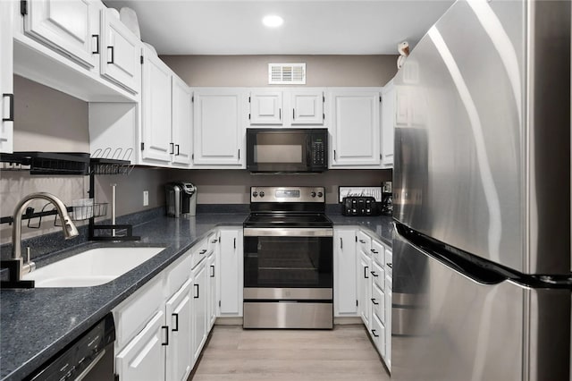5973 State Highway 361 Unit 123, Port Aransas, TX 78373 - kitchen featuring appliances with stainless steel finishes, white cabinets, light wood-type flooring, recessed lighting, and dark stone countertops