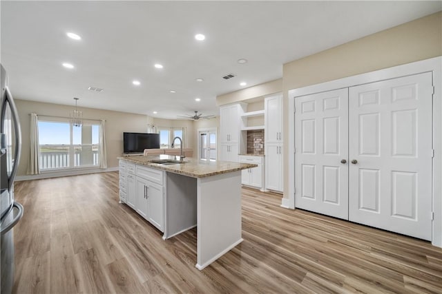 738 Crown Hbr, Corpus Christi, TX 78402 - kitchen featuring a sink, an island with sink, light wood-style floors, light stone counters, and white cabinets
