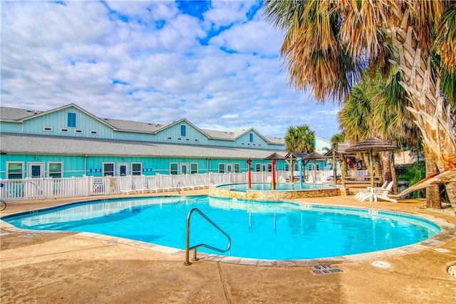 community pool with a patio and fence