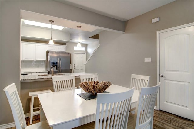 dining room featuring baseboards, dark wood finished floors, and beamed ceiling