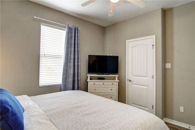 bedroom featuring baseboards, multiple windows, ceiling fan, and wood finished floors