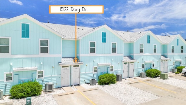 townhome / multi-family property with a shingled roof, board and batten siding, and central air condition unit