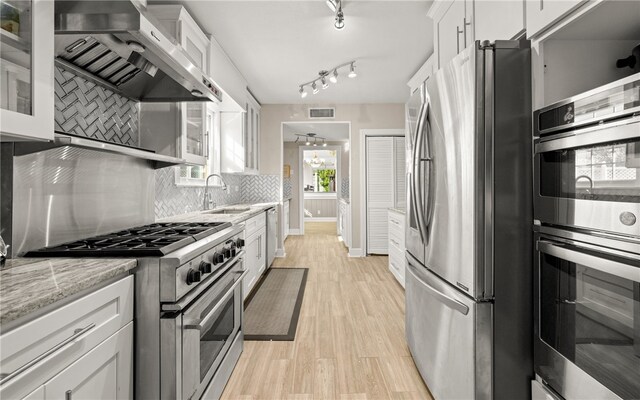 kitchen with white cabinets, decorative backsplash, sink, and stainless steel appliances