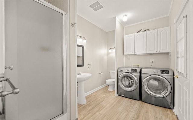 clothes washing area featuring washer and dryer, light wood-type flooring, ornamental molding, and sink